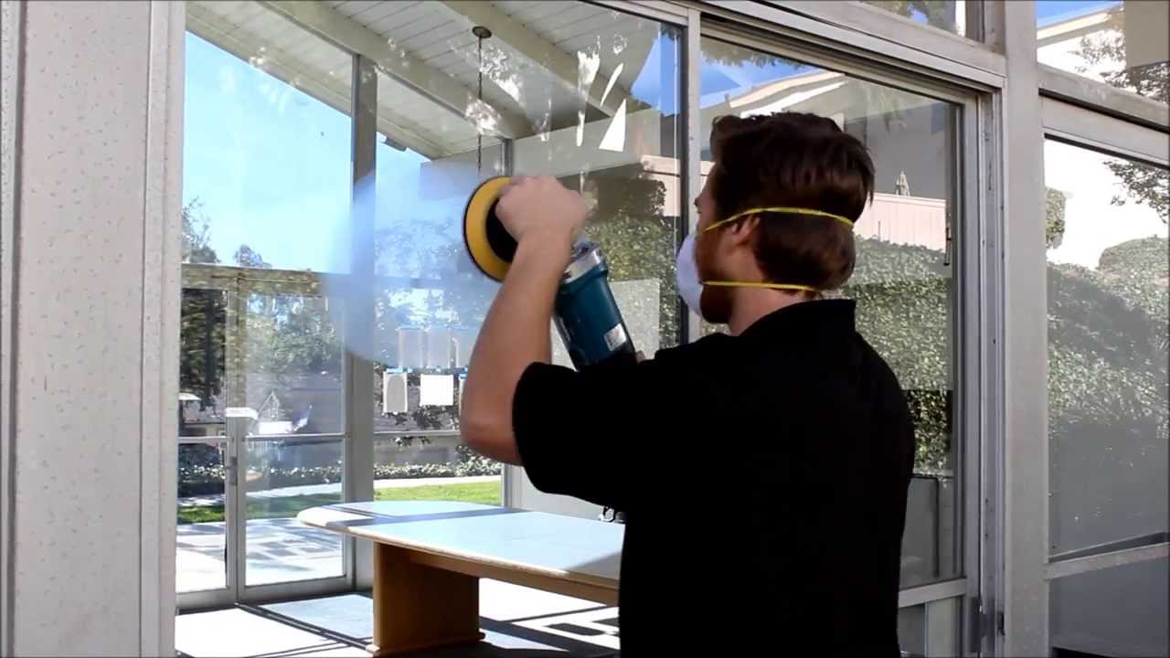 Technician polishing a residential window pane with a rotary machine
